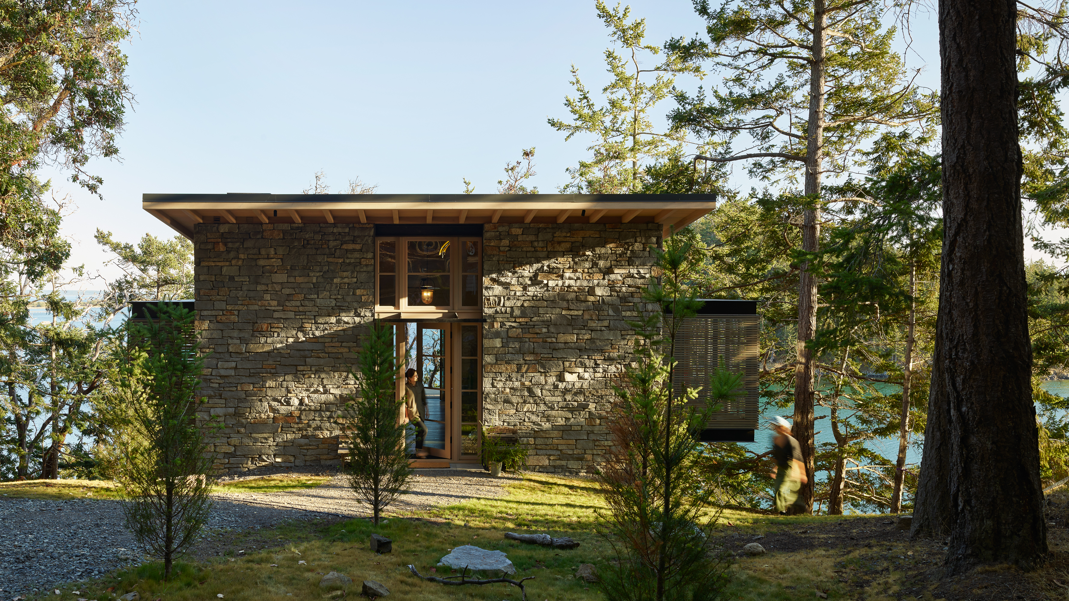 The guest house, a stone tower with innovative design, offers unique accommodations and breathtaking views of Puget Sound, blending seamlessly with its surroundings.