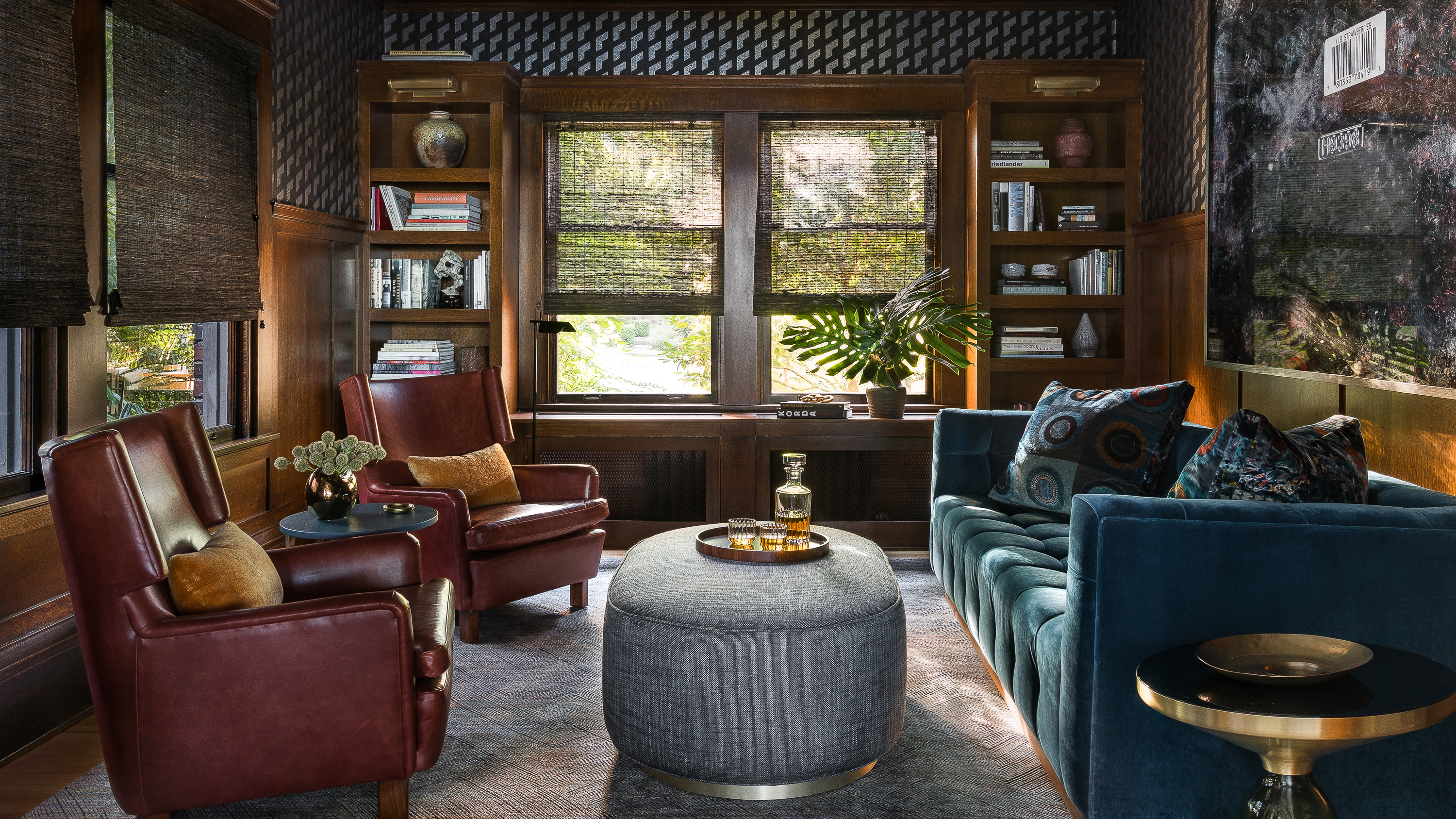 The den exudes a modern English clubroom vibe with vintage Swedish club chairs, a large photograph by Isaac Layman, and Tom Dixon brass accents.