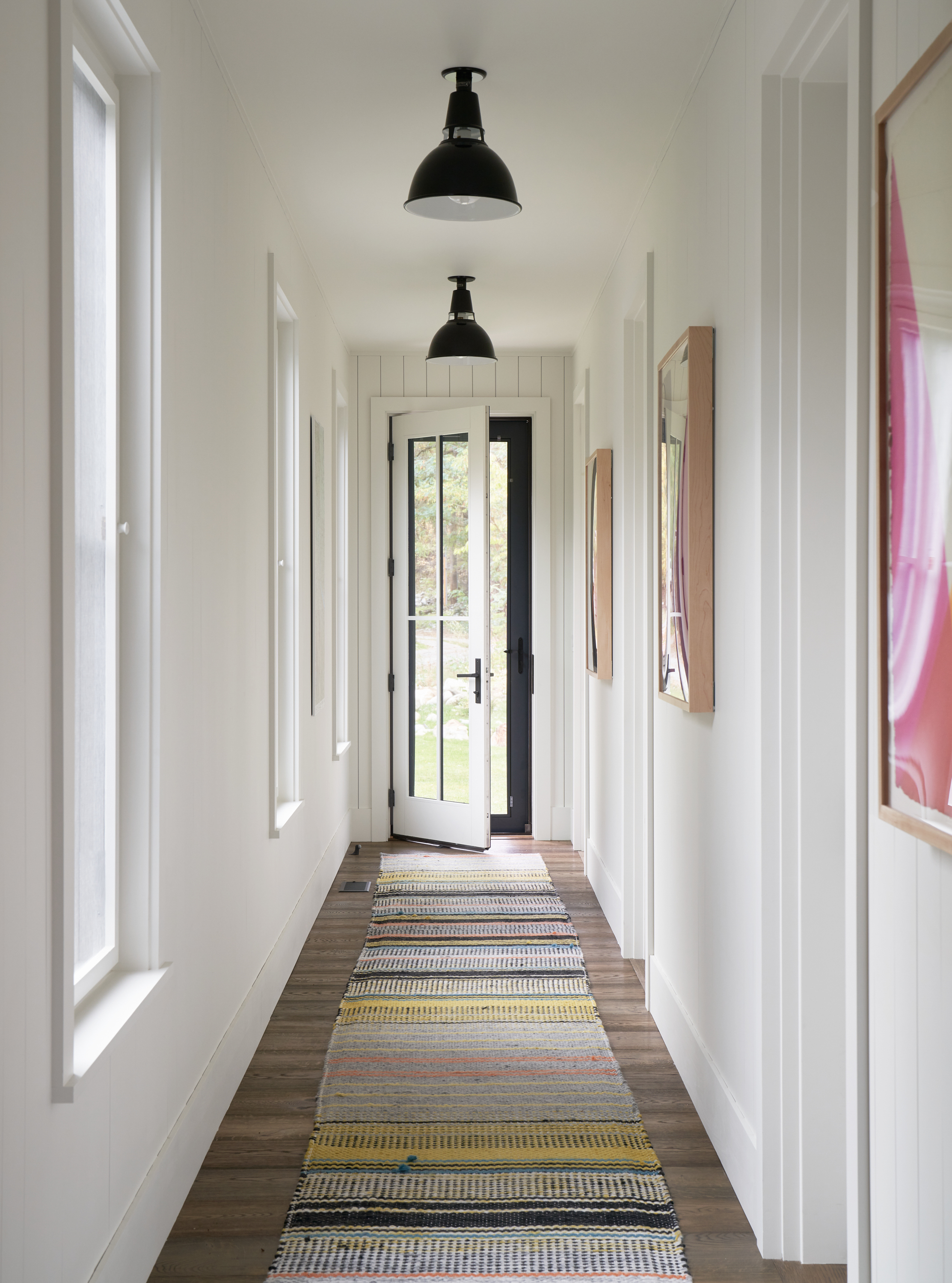 A view down the hallway of the bedroom wing, with industrial-inspired pendants overhead.