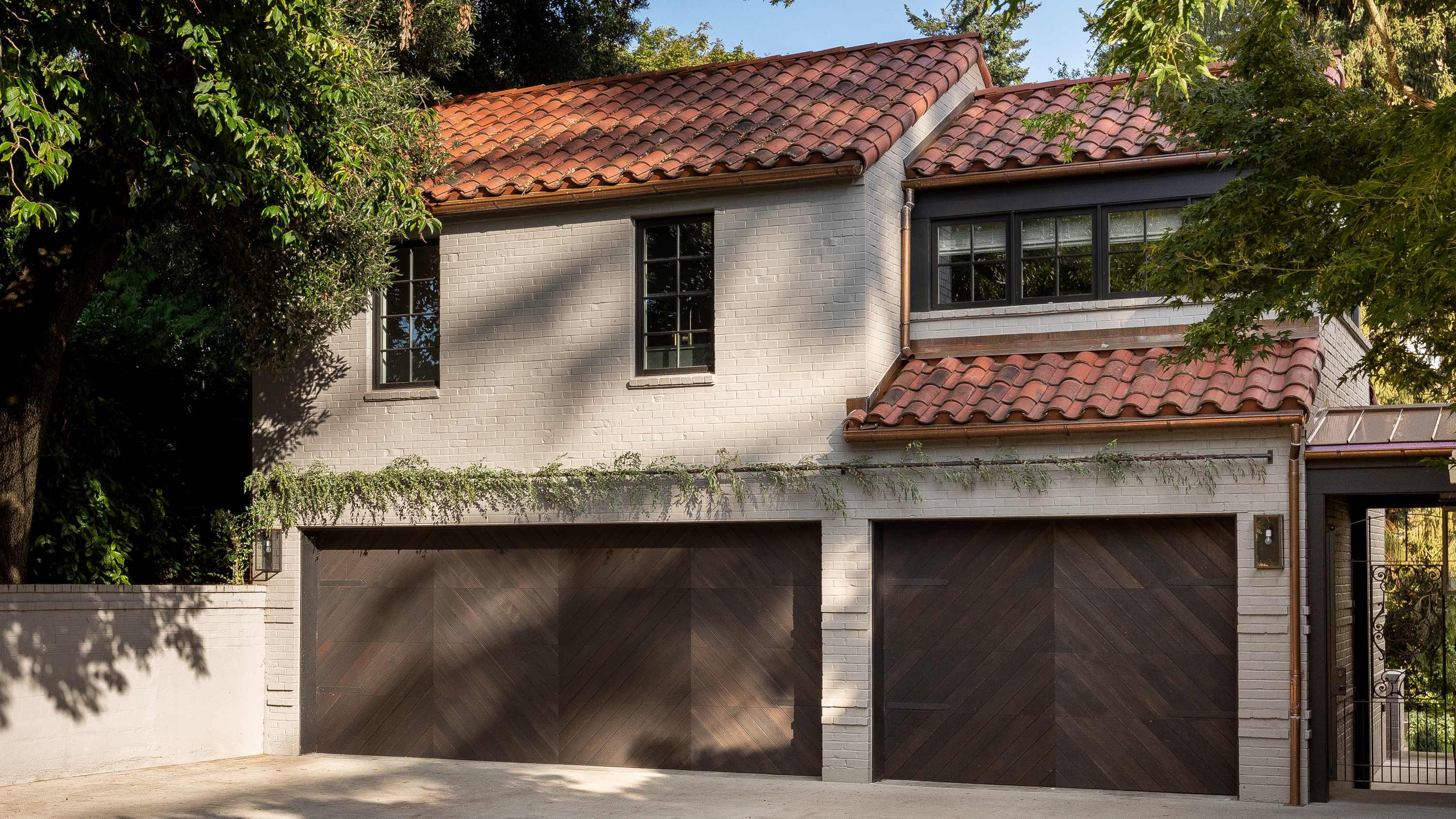 The exterior of the home remains mostly classic, while the addition above the garage introduces new materiality, blending modern modular elements with the classic architecture.
