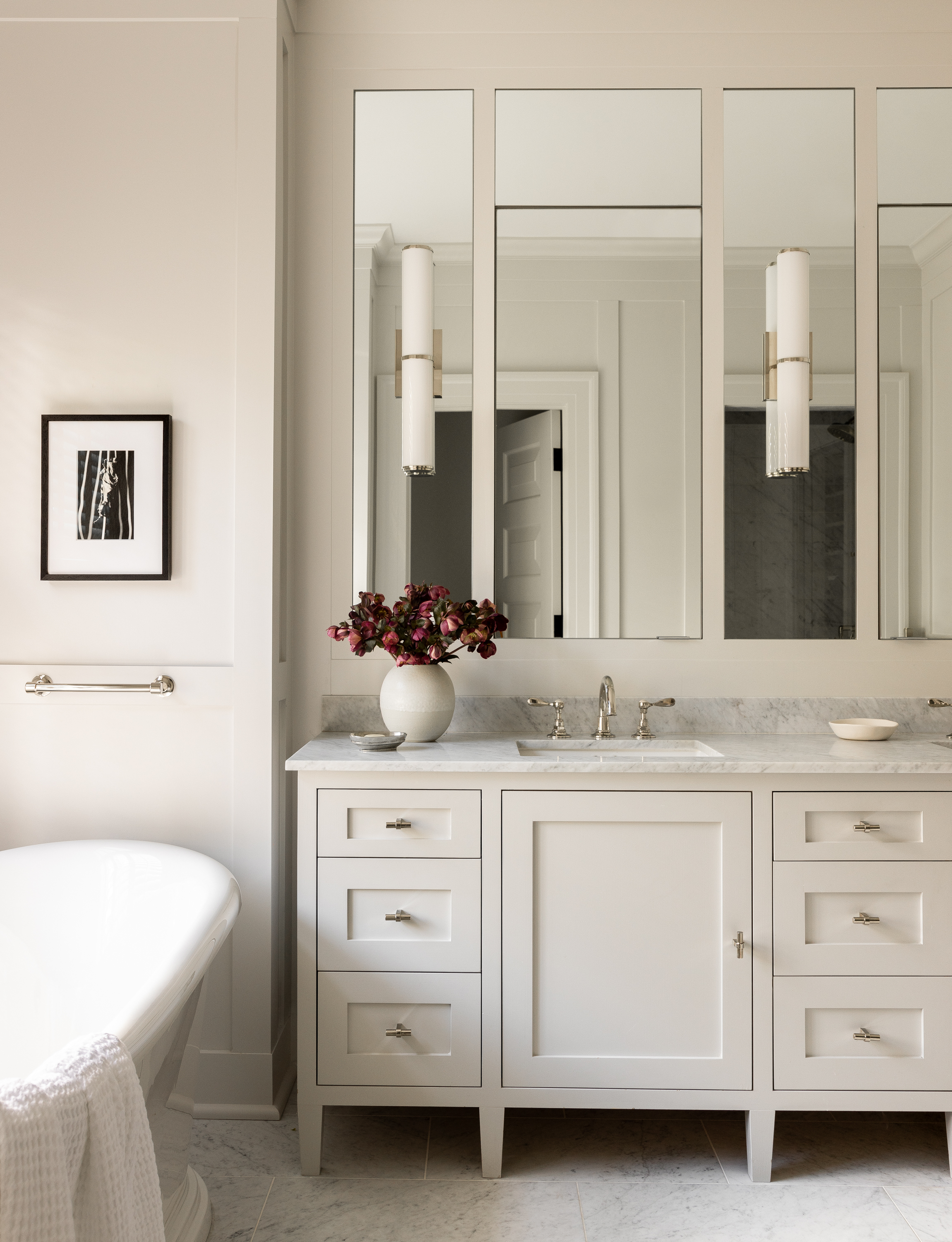 A classic and traditional bathroom vanity featuring an all-white design, chrome finishes, and vertical sconces, adding a timeless elegance.