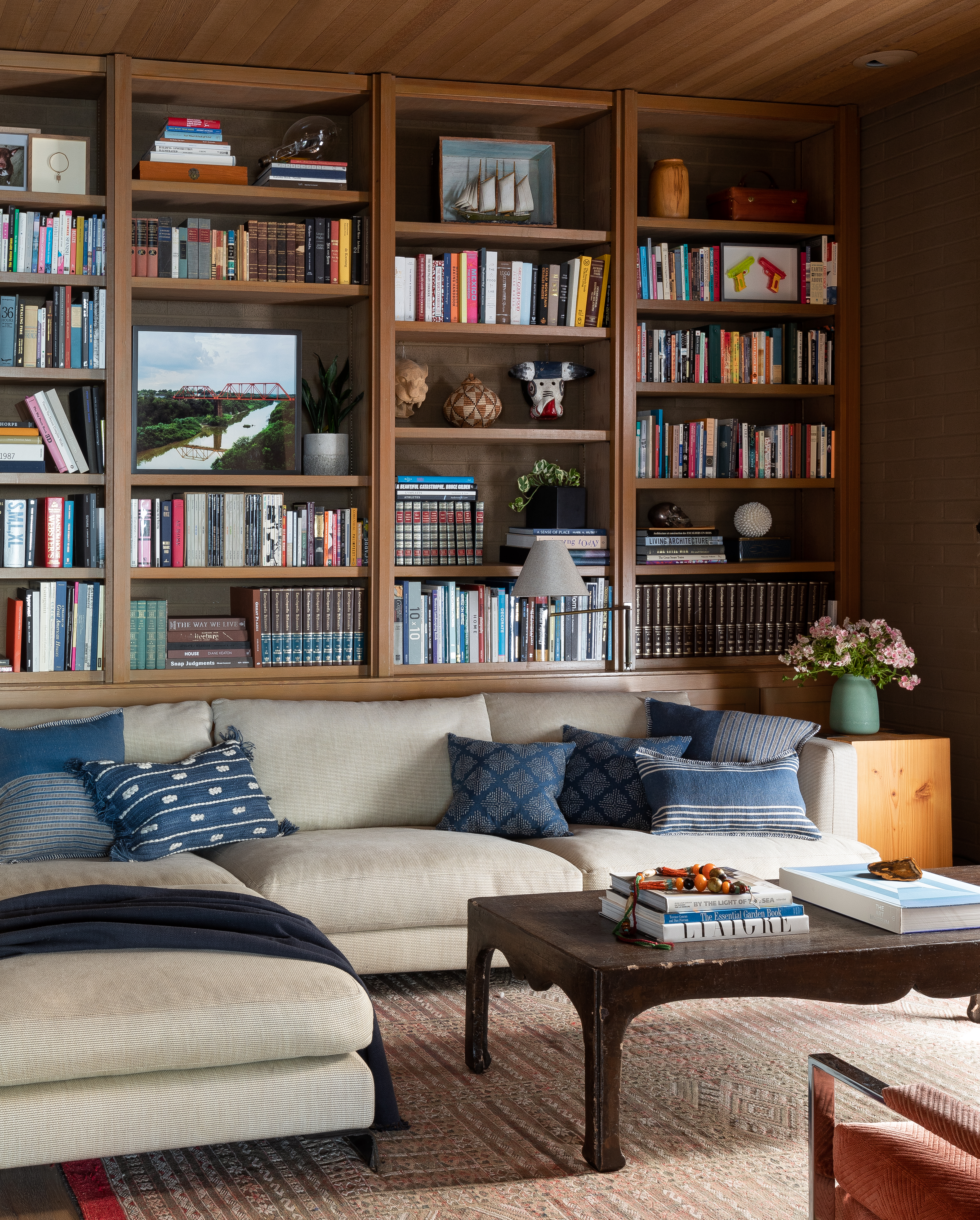 The library/office is cozy and practical with built-in shelving and storage. A collection of books and artifacts lines the entire wall, reflecting the owner's travels and studies.