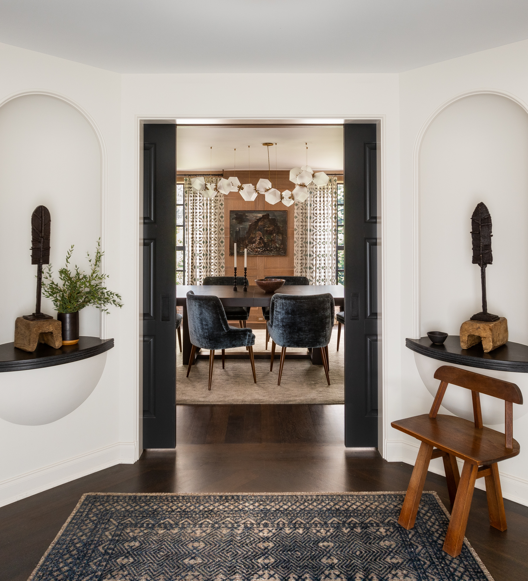 Entry looking into the dining room, showcasing niche wall cutouts with sculptures and a vintage wood chair.