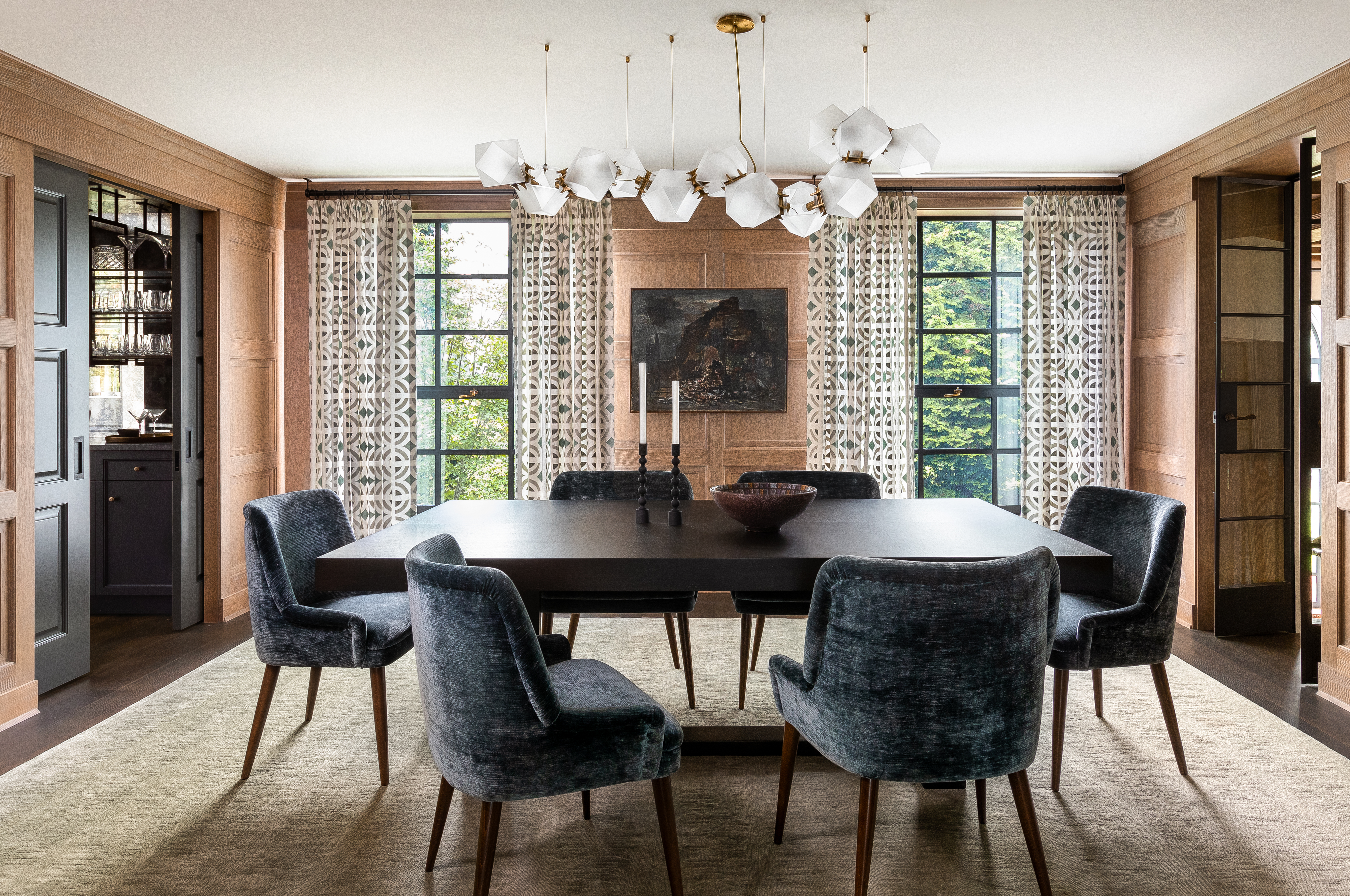 Dining room featuring a Gabriel Scott chandelier, Michael Berman dining table, Fiona McDonald dining chairs with Zoffany fabric, detailed oak wall paneling, and artwork by Charles Freger.