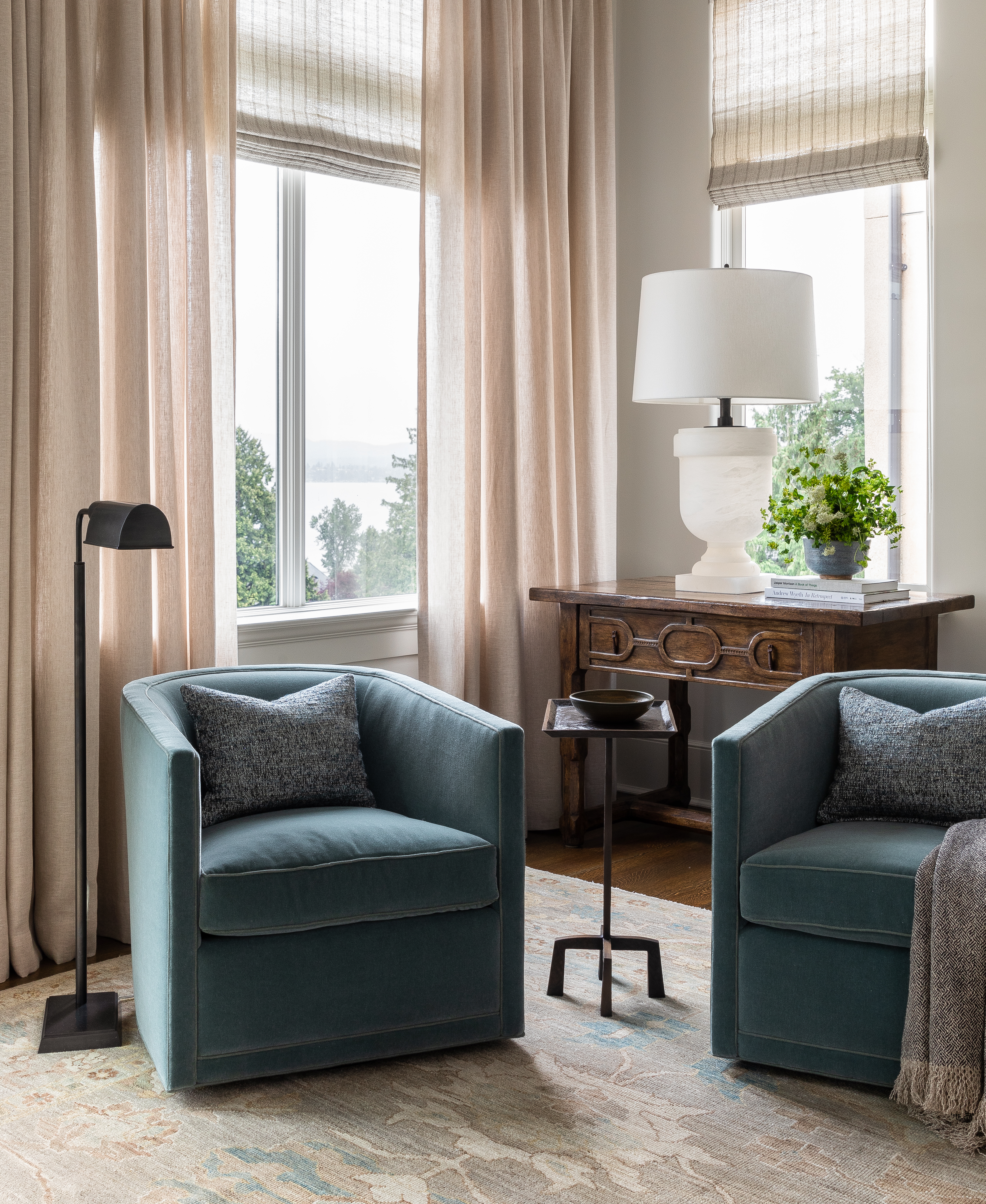 Twin barrel-back swivel chairs, carved front console tables, and a custom woven rug create a blue, brown and gray color story.