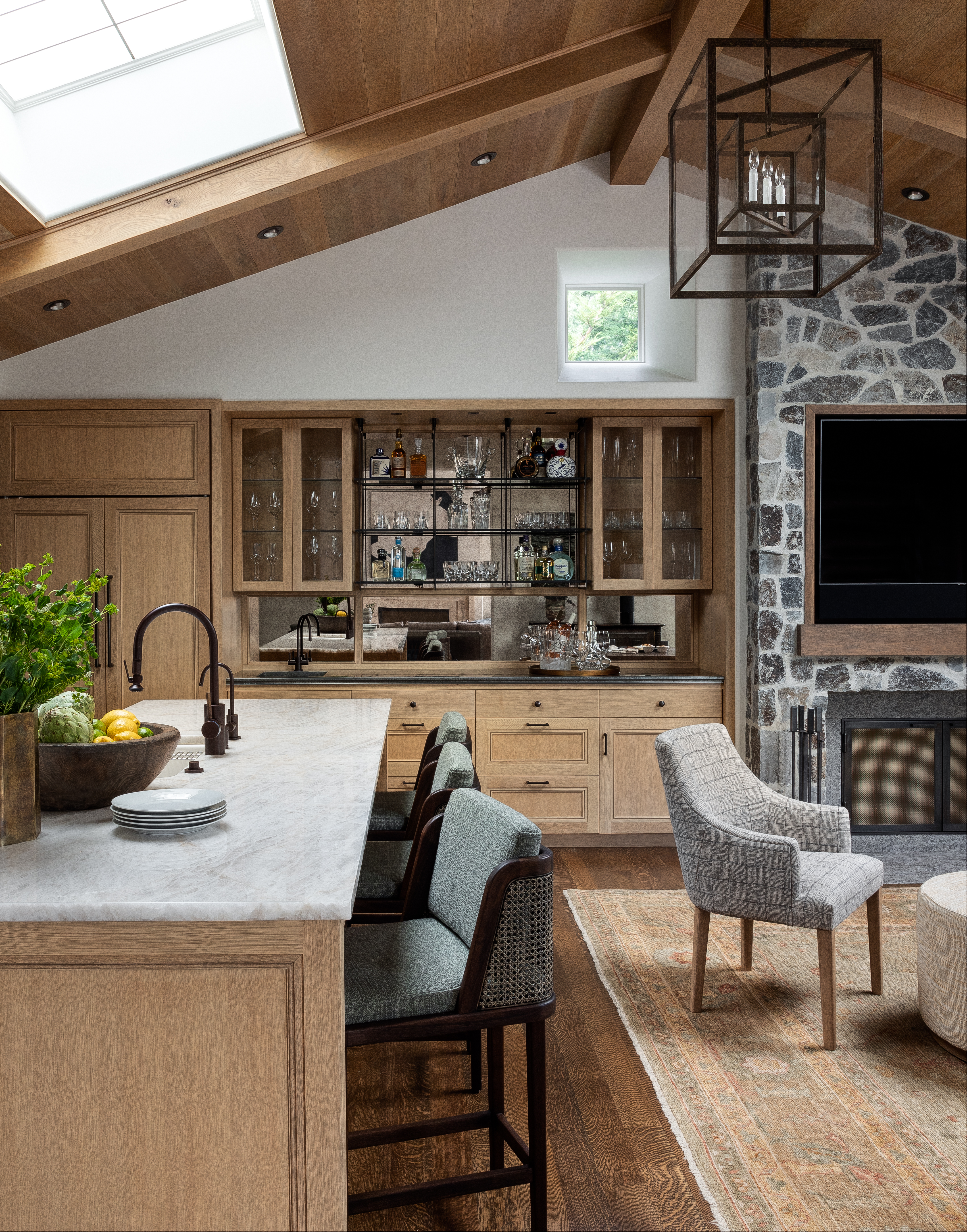 The kitchen-dining area was given a sense of age with the addition of a stone wall, fireplace, paneling, and beams.