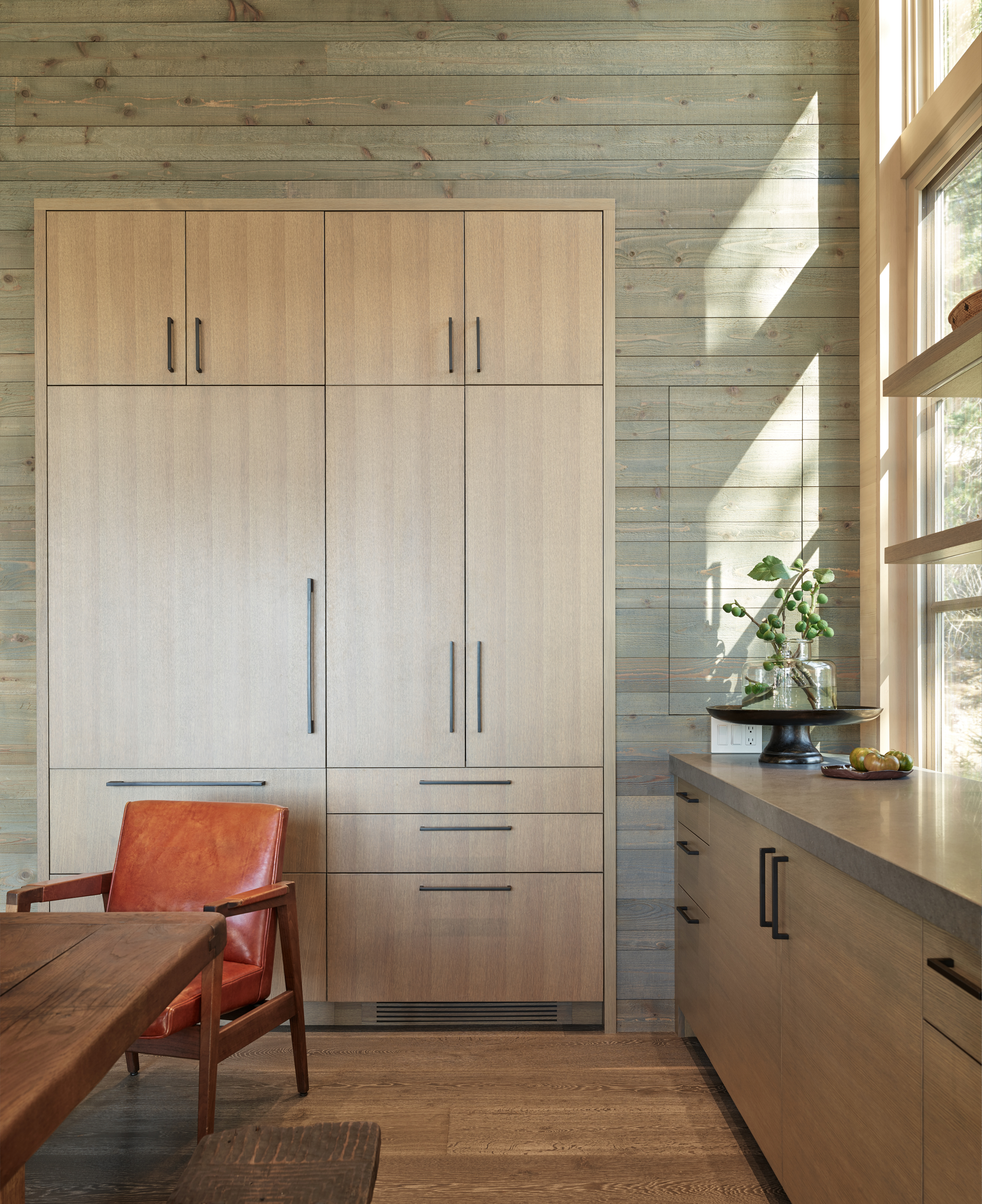 The cabinets and concealed refrigerator are wrapped in various types of wood, adding warmth and texture to the kitchen space.