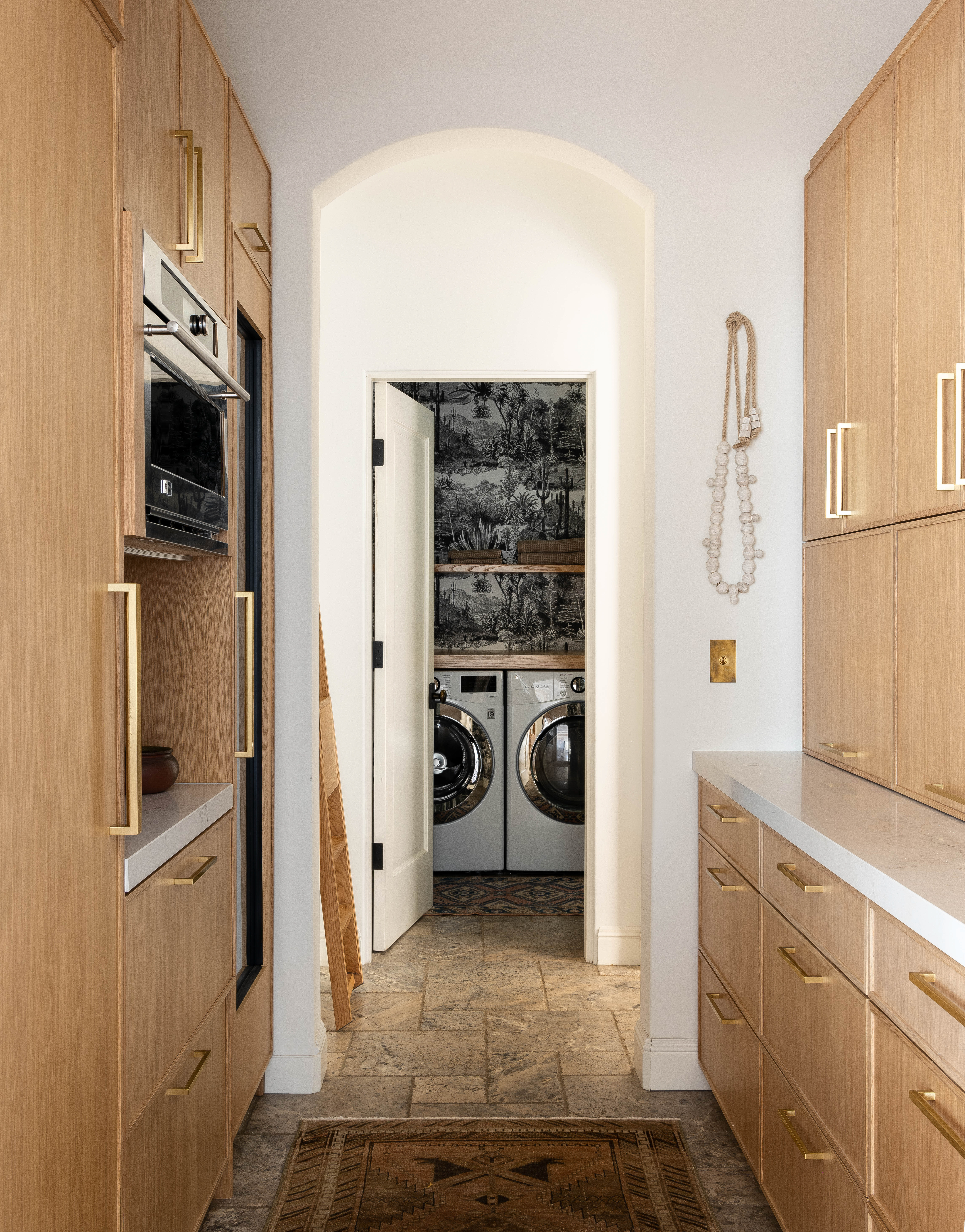 Laundry room and butler pantry with striking black and white desert scene wall covering. The design features arched doorways for added elegance.