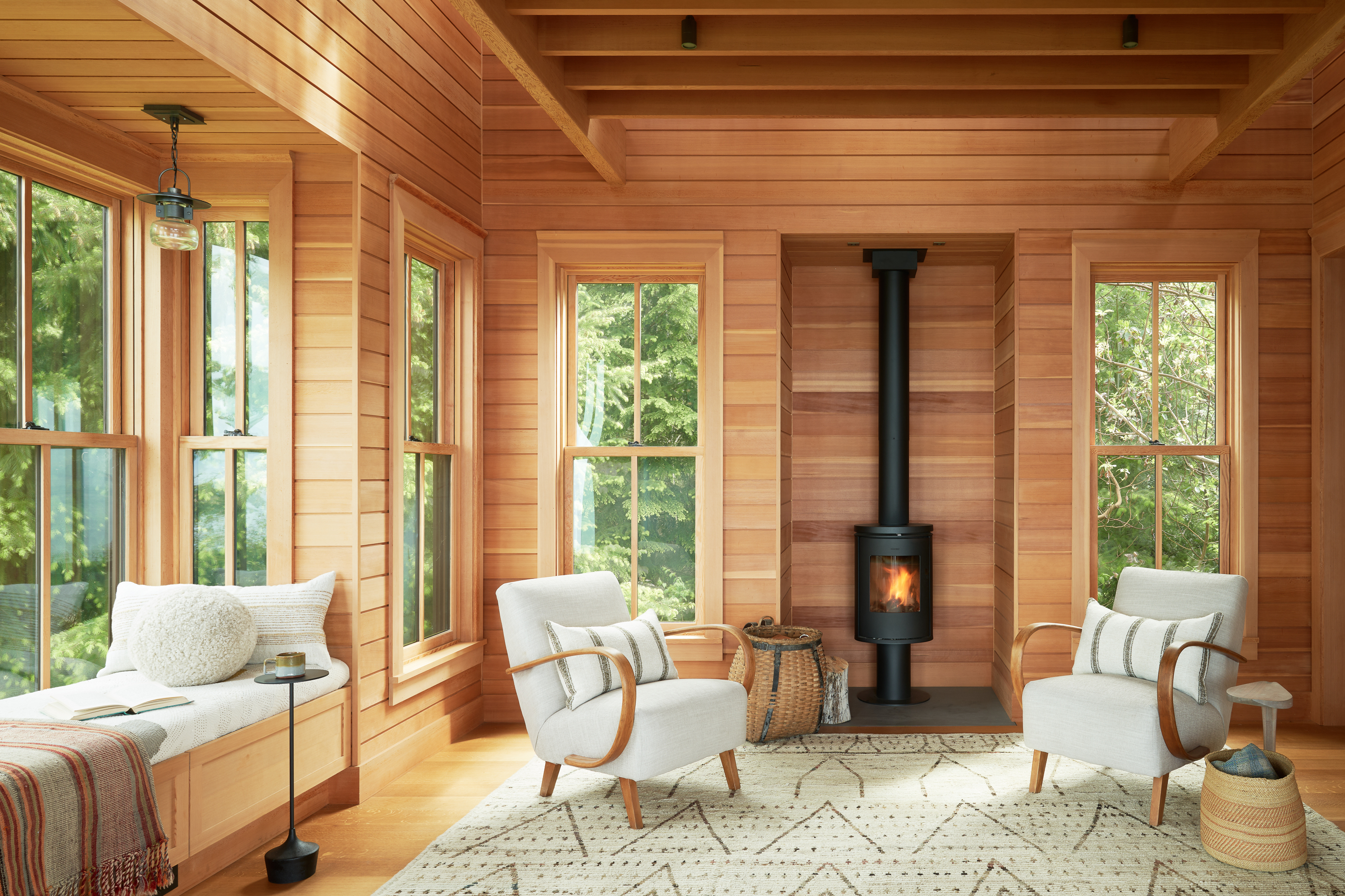 Bright and warm cedar clad living space with a wood burning stove.