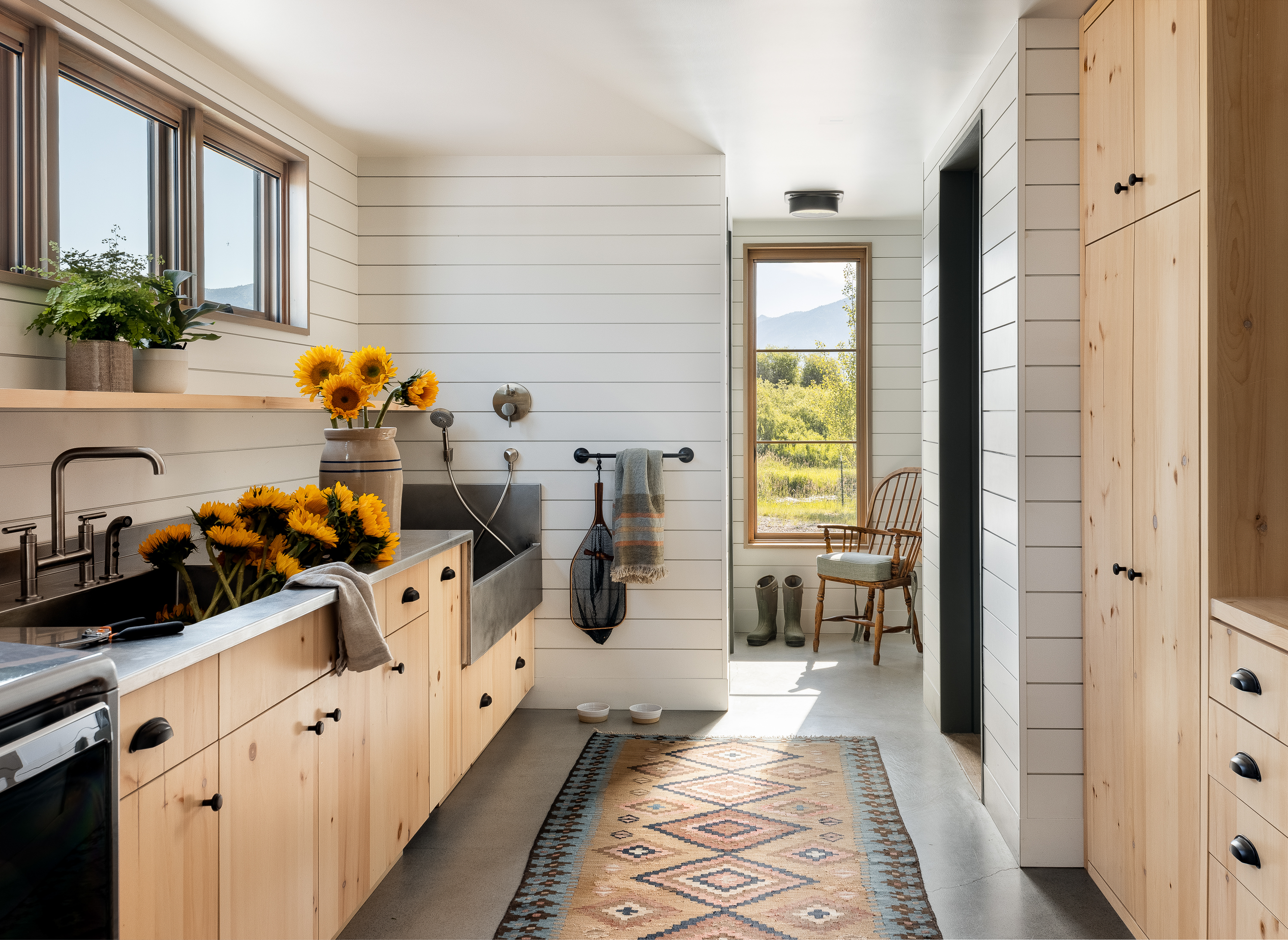 Bright Mudroom with shiplap paneling and natural pine cabinets. Sun flowers resting in the sink.