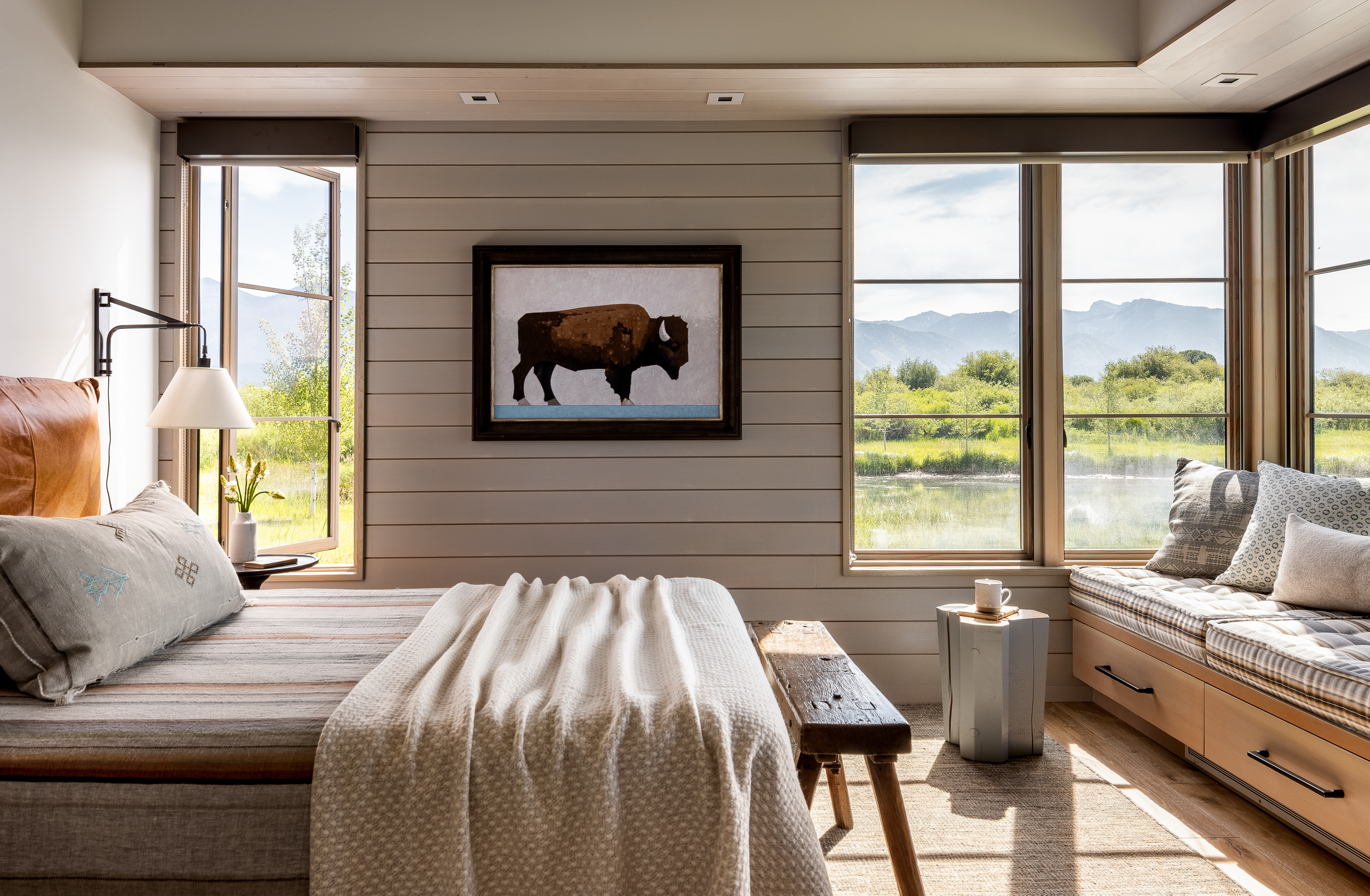 Natural wood panel bedroom, leather headboard bed, and built-in window seat with views of Wyoming landscape.