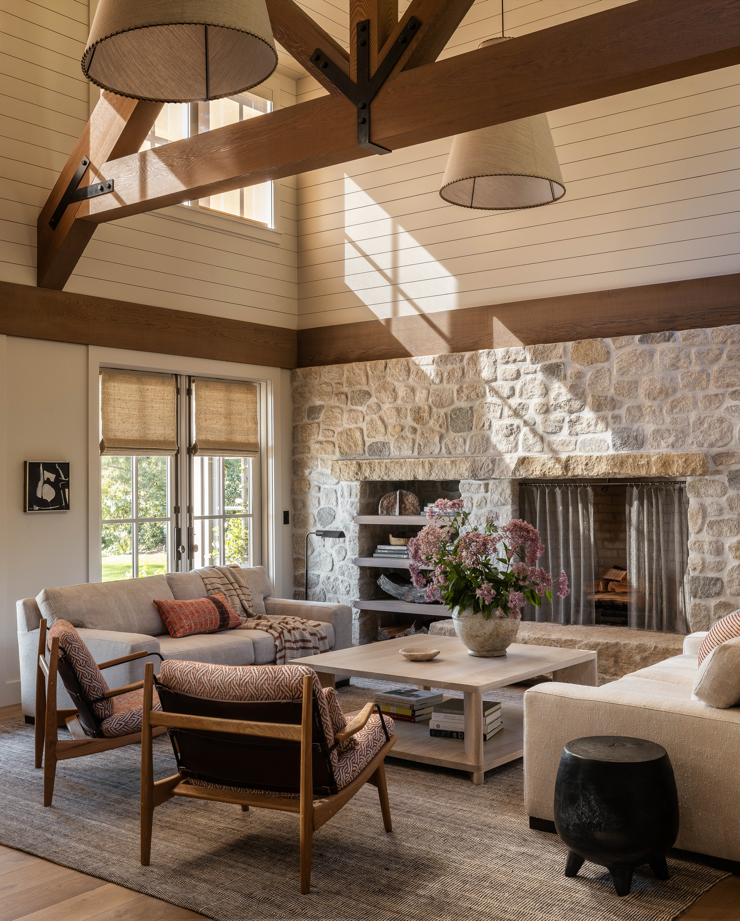 A shot capturing the high ceilings in the living room, highlighting the intricate timber trusses and stunning large-scale custom pendants creating an inviting and impressive atmosphere.