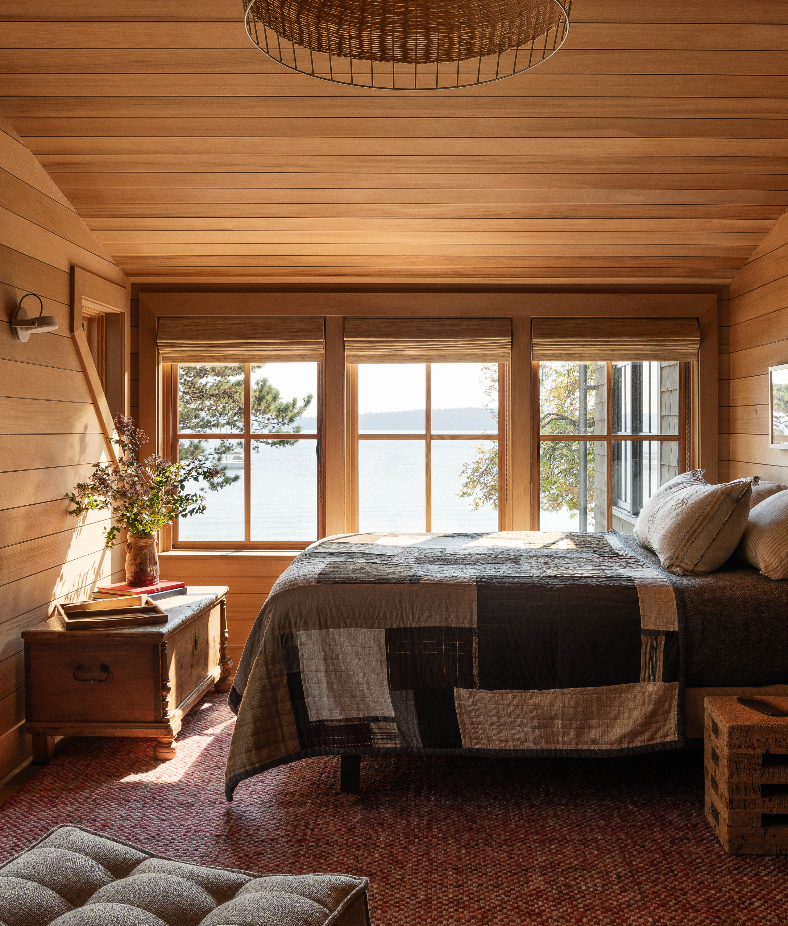 The bed in this room, once an extra lounge space, now serves as a cozy retreat with views of the lower pine boughs and the cityscape across the sound, capturing the essence of a waterfront treehouse