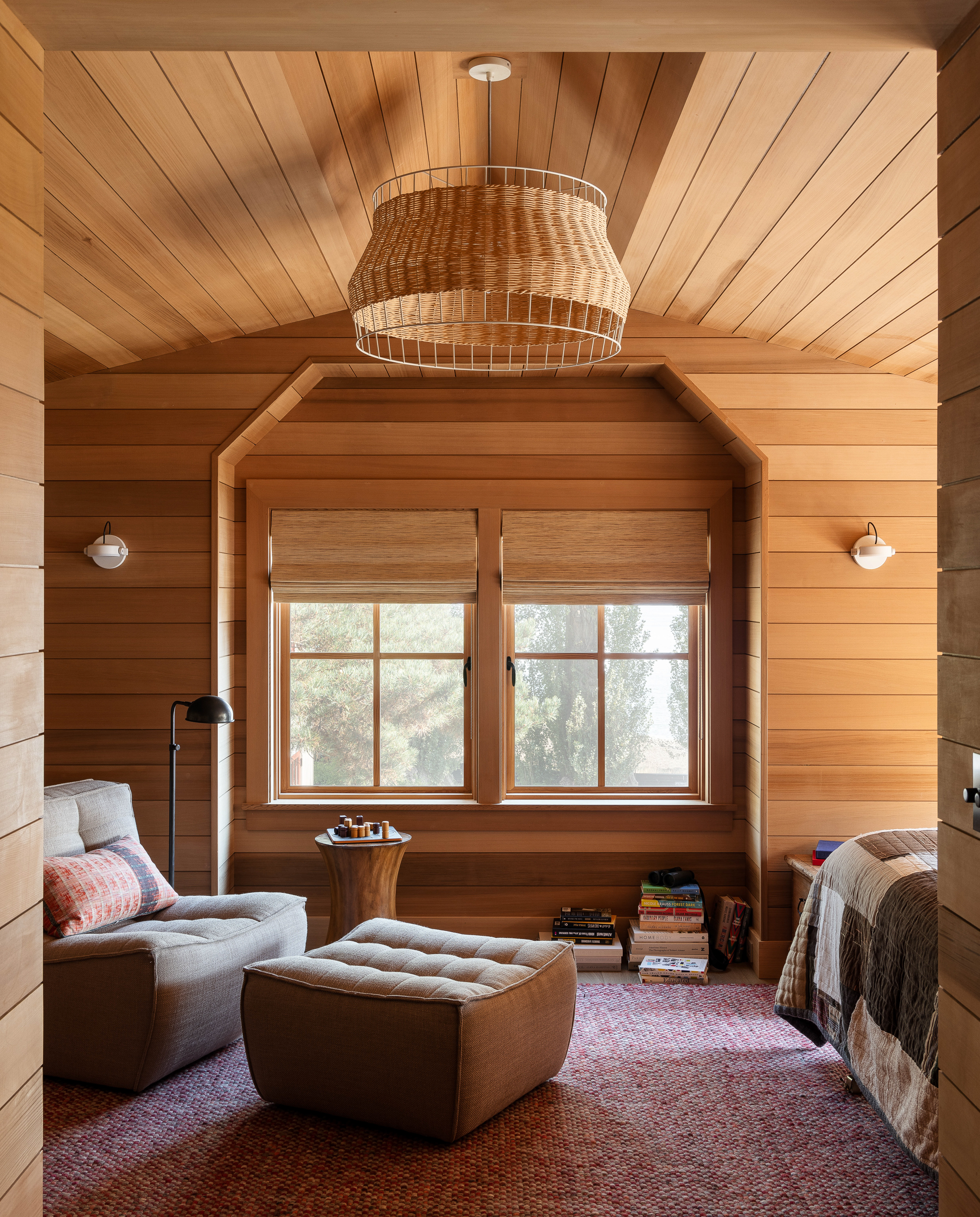 The seating area in this room, designed as a classic sleeping porch, offers a treehouse-like ambiance with its unfinished cedar paneling and expansive windows.