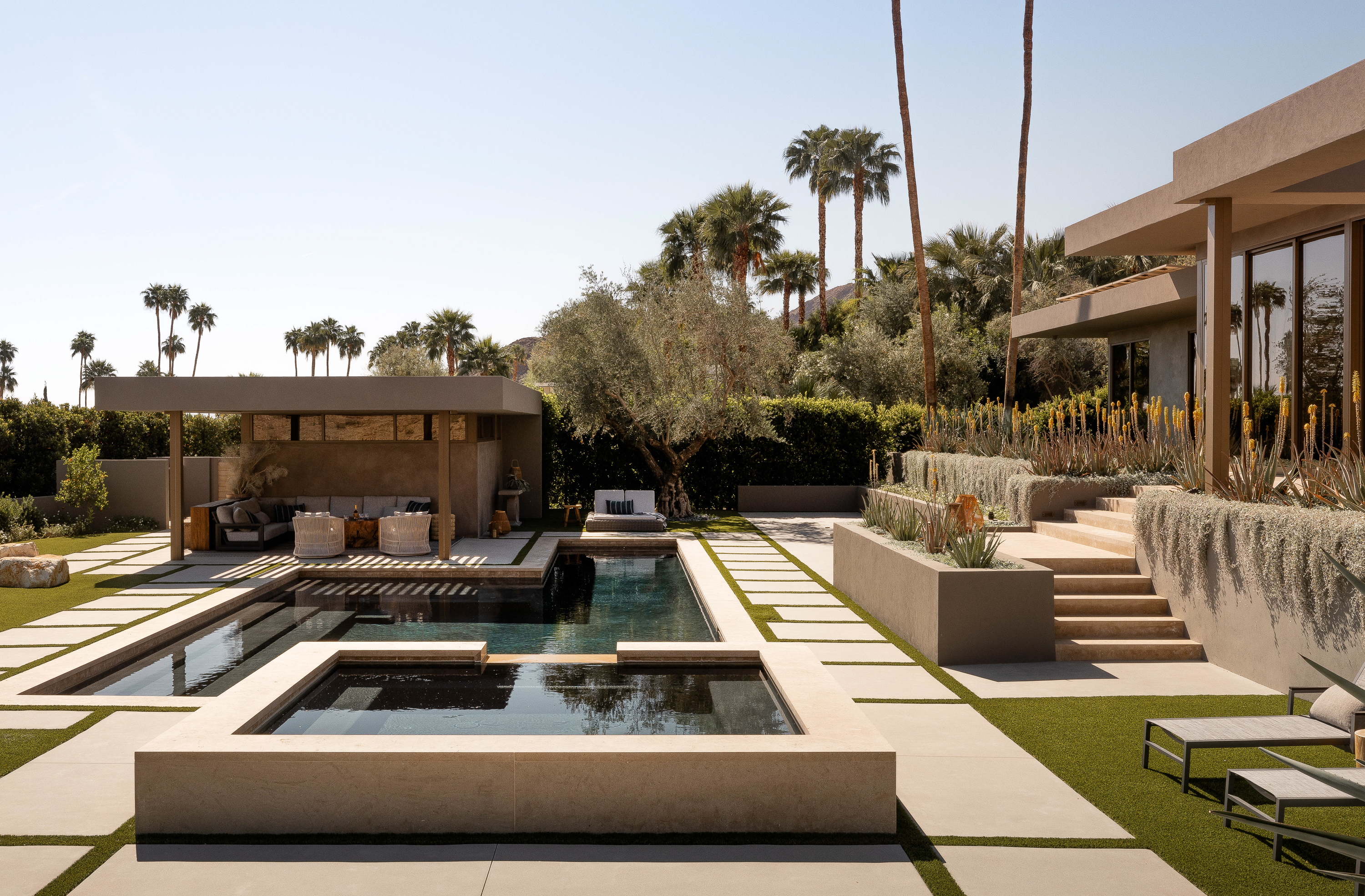 Pool area at Palm Sprinfs Retreat: Large cement pavers surround the pool, offering a contemporary and durable surface for lounging and enjoying the desert sun.