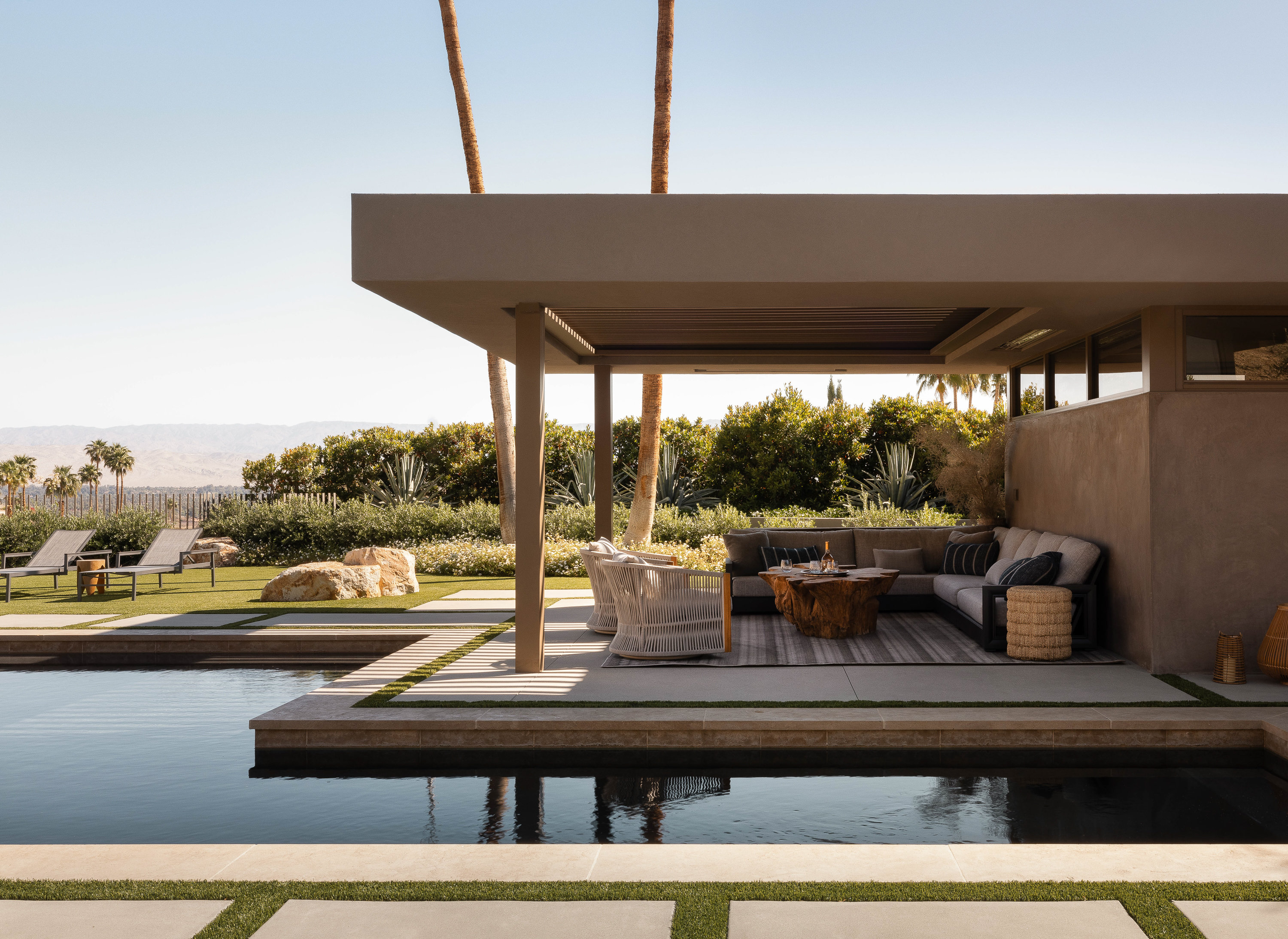 The outdoor living room is the focal point, with the exercise room's roof extending to create shade for the poolside sectional, offering a perfect spot for relaxation