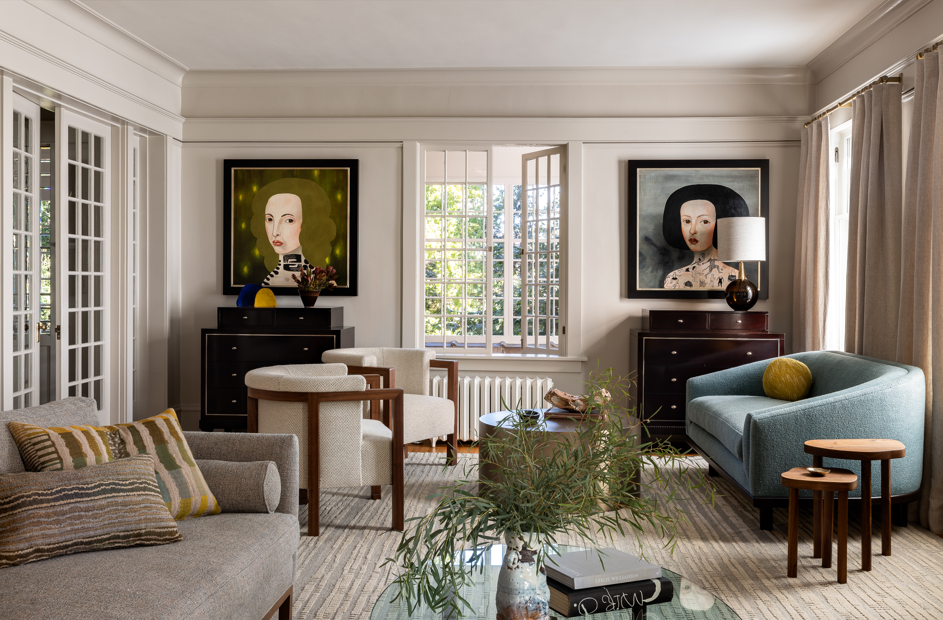 Living room hero shot featuring portrait oil paintings and furniture by Dmytri & Co, Tagore Chair, and a Custom Nickey Kehoe Curved Sofa.