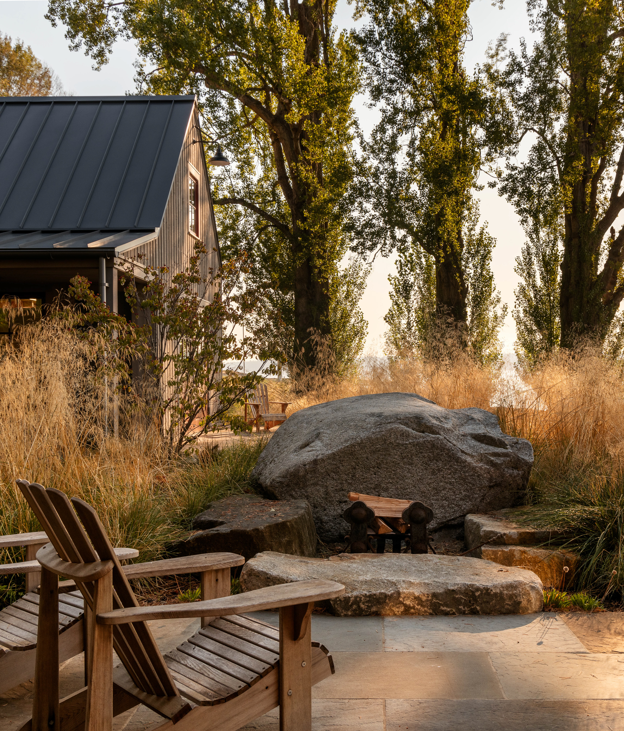 View of the fire pit on the patio, where large boulders have been thoughtfully incorporated to seamlessly blend with the natural landscape, creating a captivating outdoor space that harmonizes with the surroundings.
