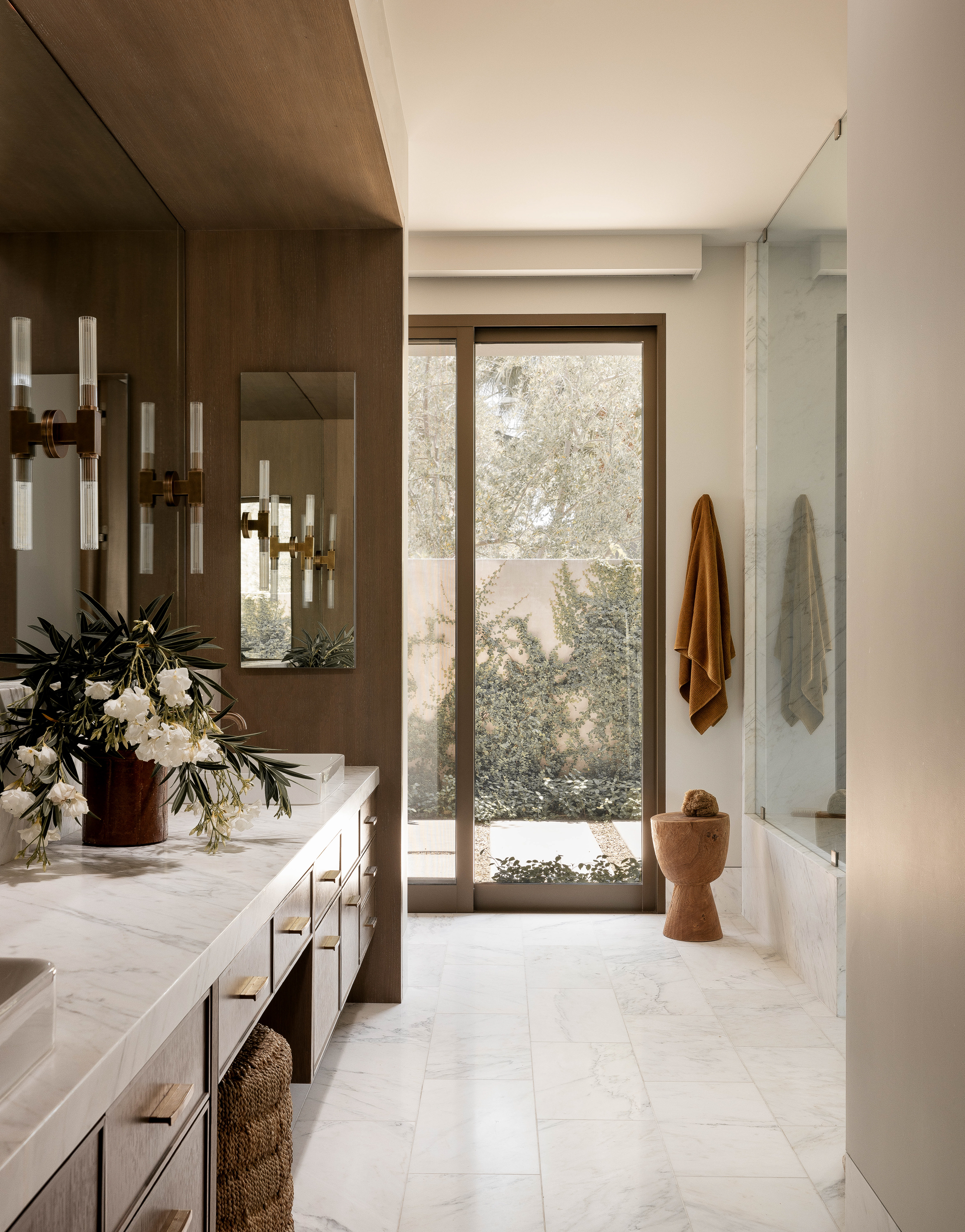 Primary bathroom at Palm Springs Retreat: A luxurious oasis with a walk-out walled shower backdrop, offering a warm and earthy contrast to the stone environment
