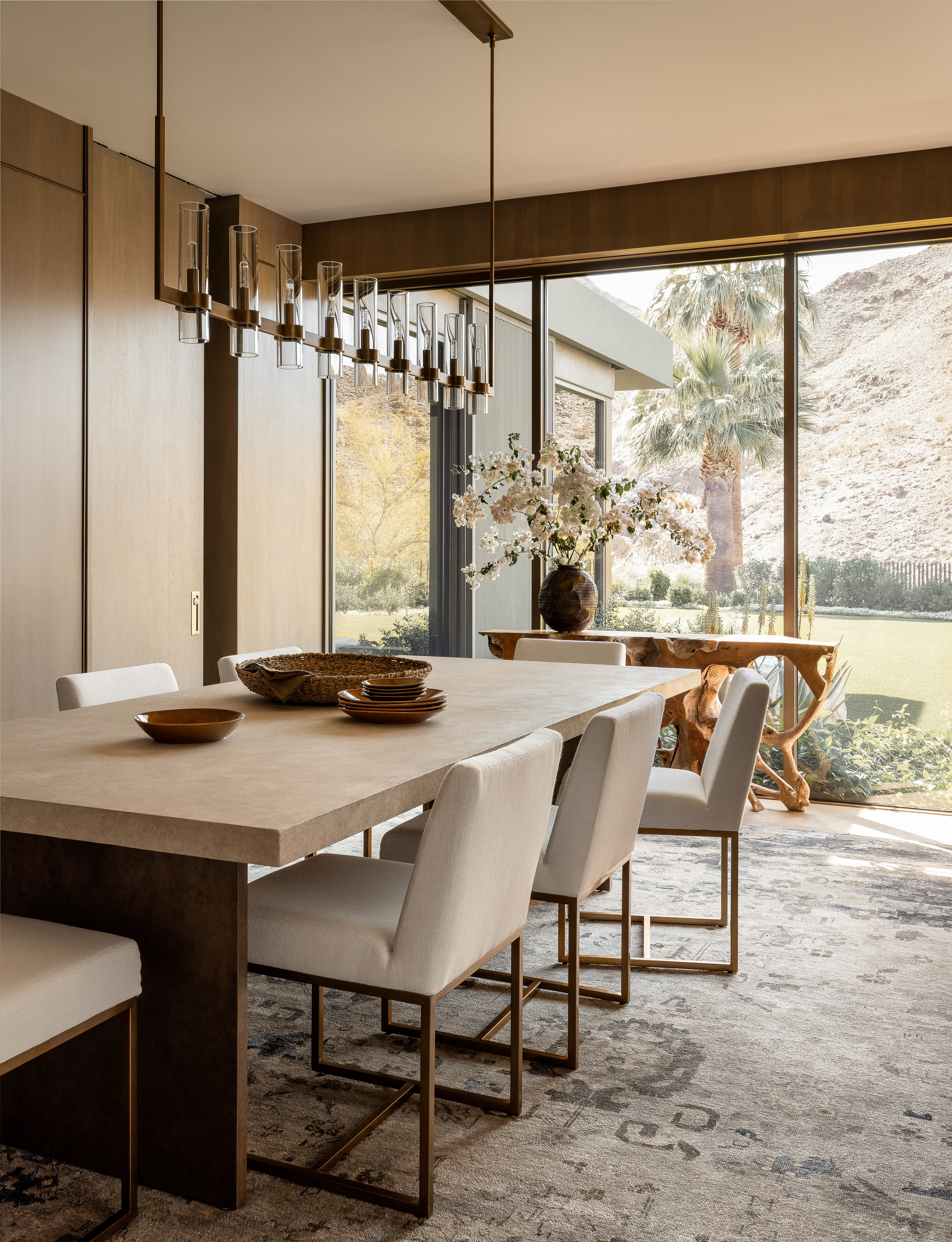 Dining room at Palm Springs Retreat: Oak and brass paneled walls, with views into the guest wing, offer an intimate dining experience in a modern desert setting.