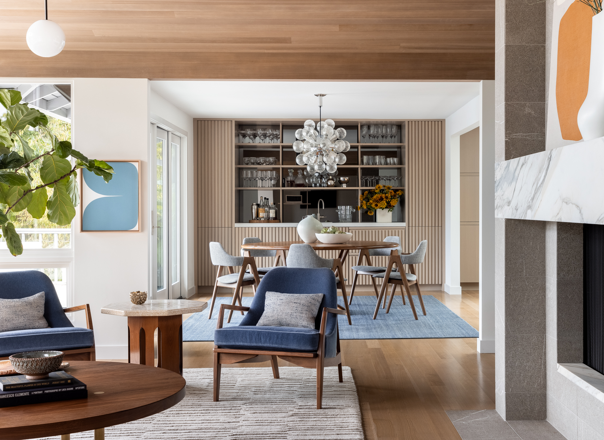 Mid Century Furniture surrounds a tile and marble fireplace, the room is accented by light washed wood ceiling and floors.